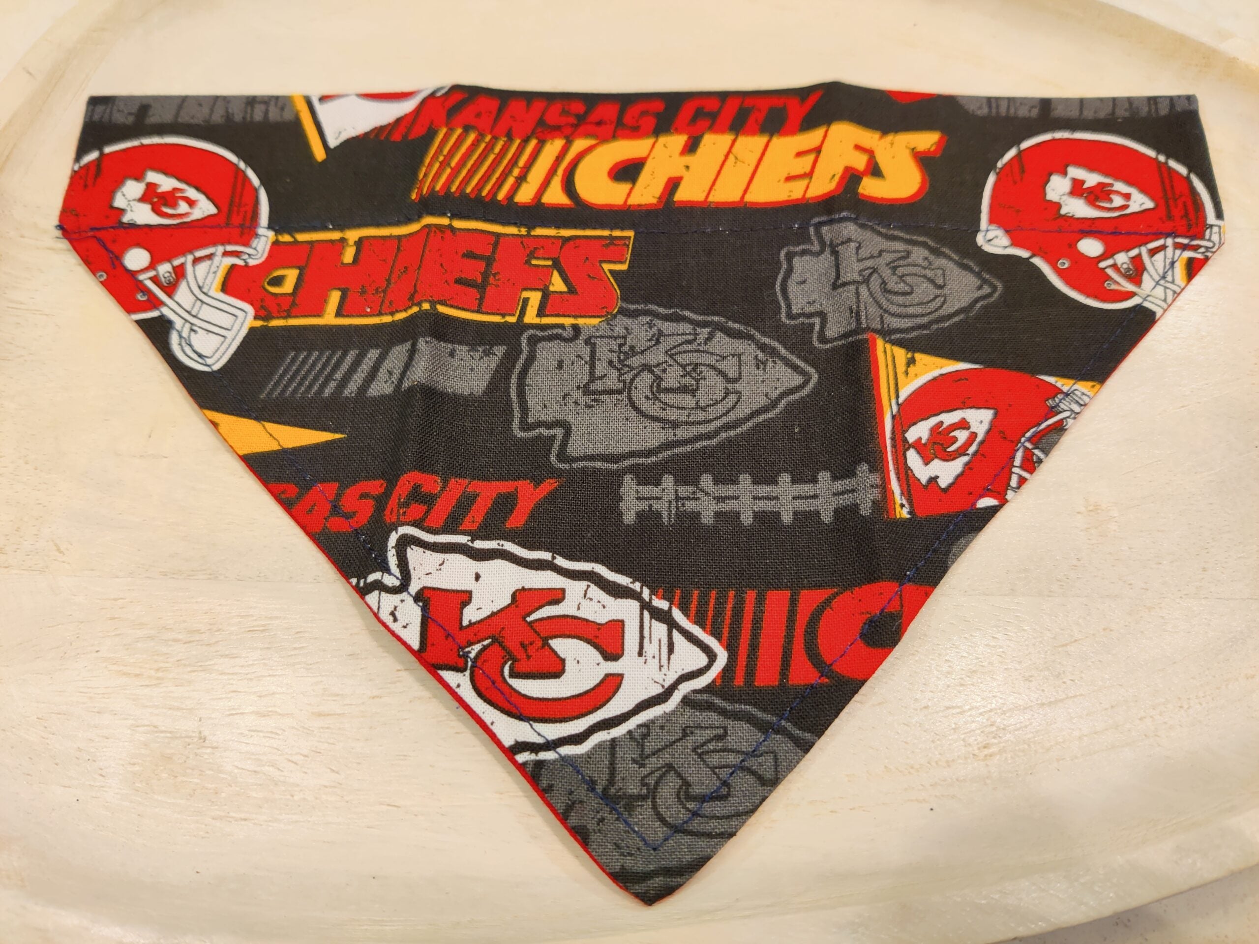 Kansas City Chiefs bandana with team logos on a beige background